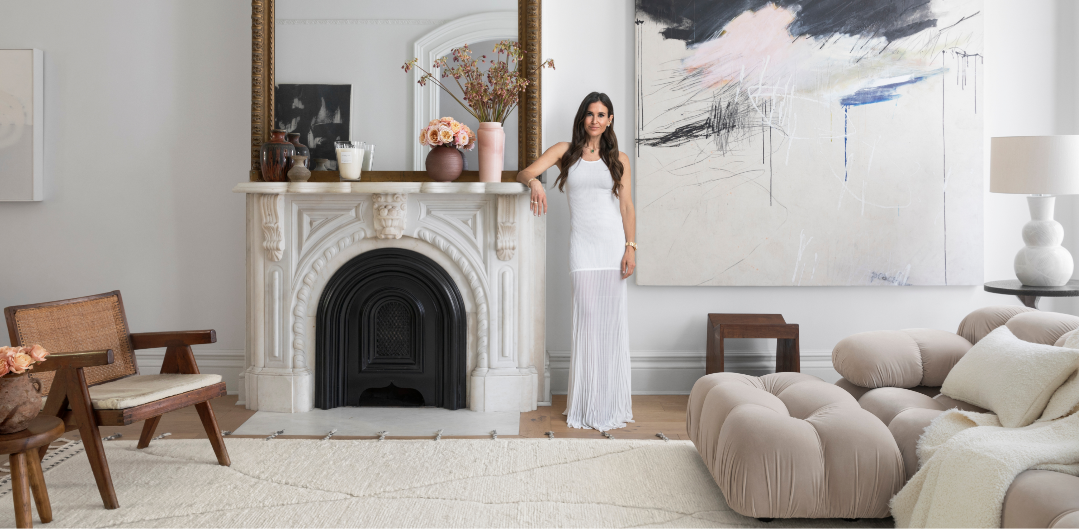Woman in a white dress standing in a stylish living room with modern decor.