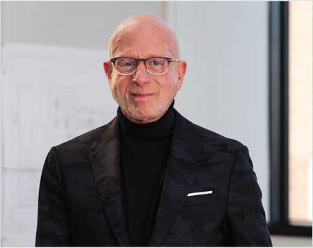 Man wearing glasses and a black suit in an indoor setting