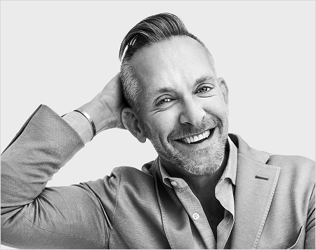 Man with a stylish haircut and beard, wearing a suit, on a white background
