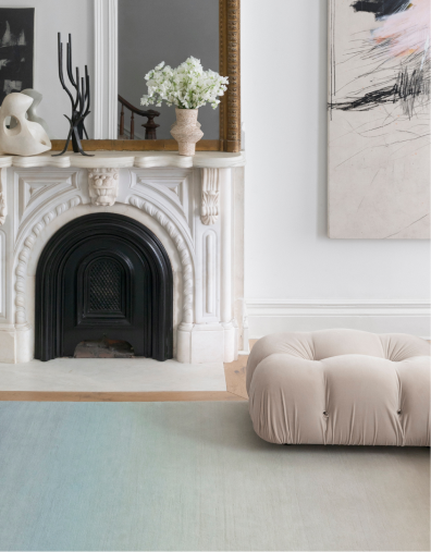 Living room with large designer rug, fireplace, and puffy chair.