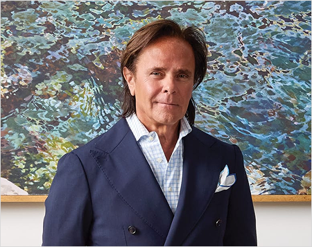 Man in a navy blazer standing in front of a colorful abstract painting