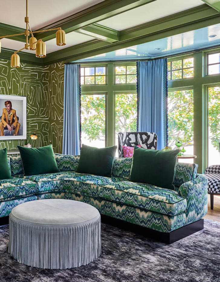 Professionally designed living room highlighting green paint and multicolored sofa on a blue designer rug.