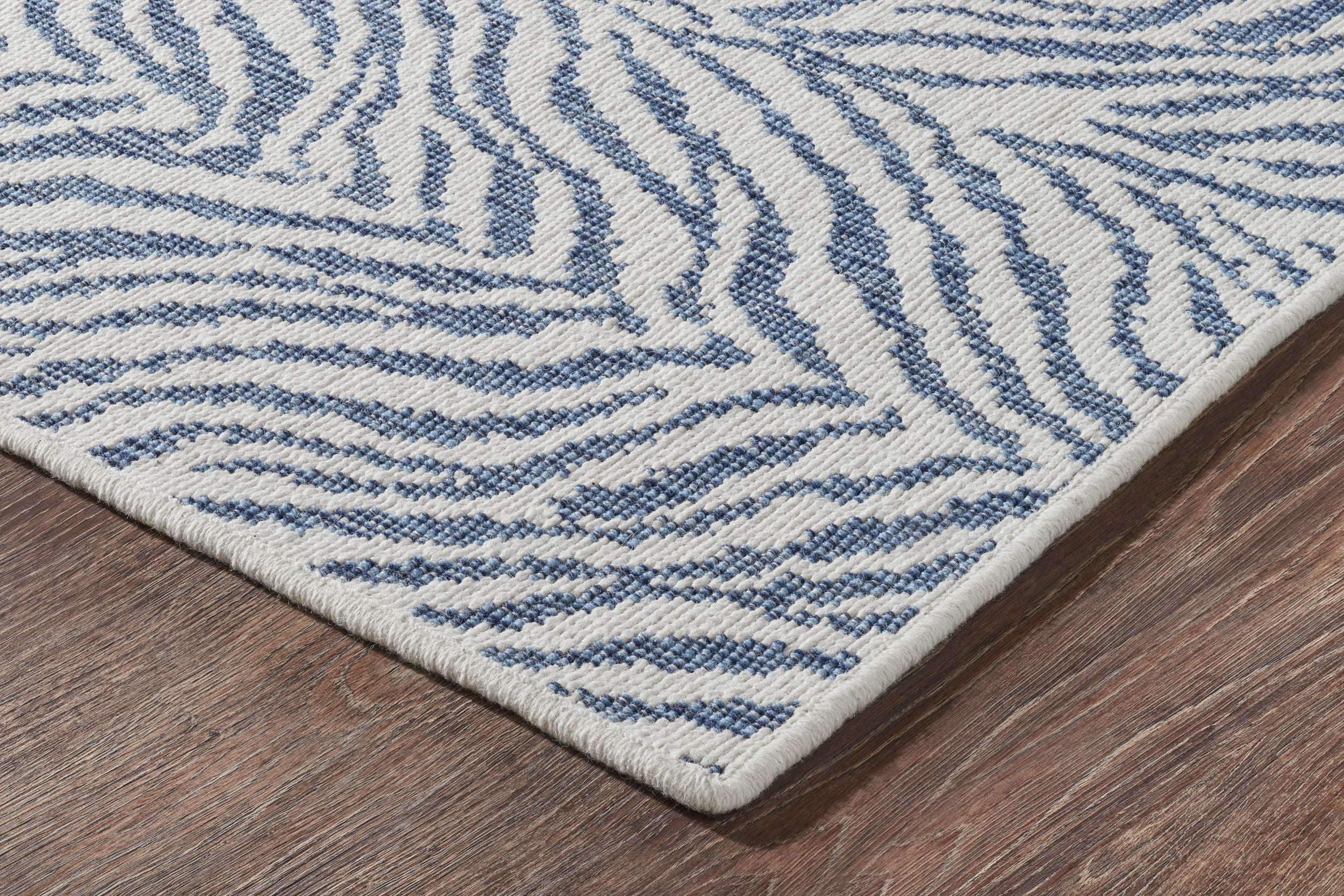 Corner of designer rug with blue zebra print on white base.
