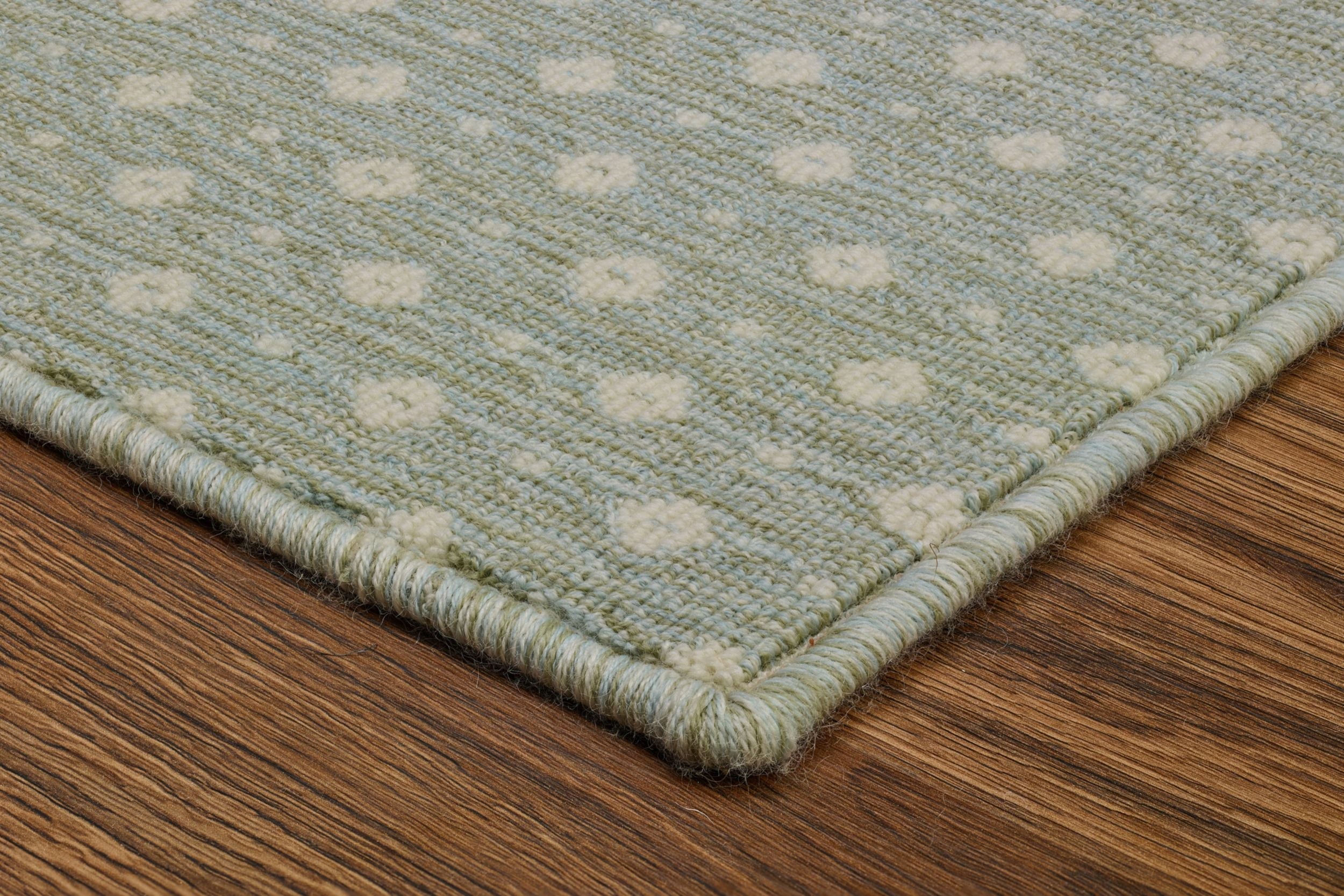 Corner of a light green patterned rug.